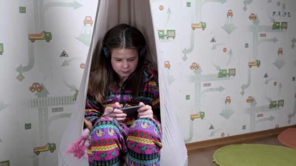 Adolescente jugando juegos en línea en el teléfono en casa . — Vídeo de stock