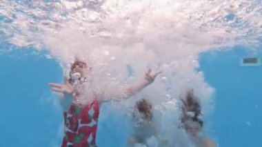 Çocuklar yaz tatilinin tadını çıkarıyor. Mutlu bir arkadaş grubu yazın güneşli bir günde havuza atlayıp havuza dalıyor. Ağır çekim. Su altı görüntüsü