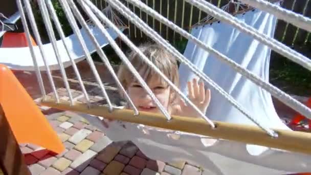 Дитина Насолоджується Літніми Канікулами Щасливий Хлопчик Махає Руками Посміхаючись Гамаку — стокове відео