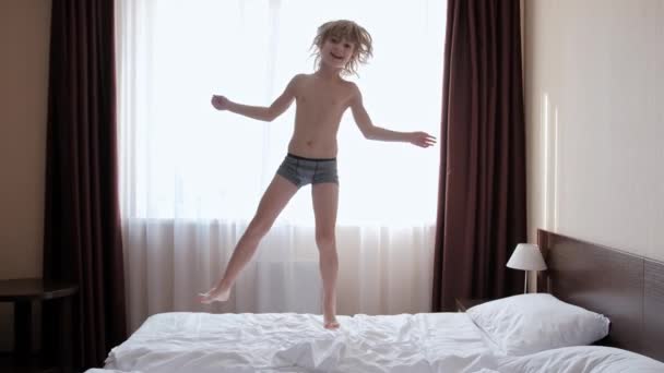 Щаслива дитина стрибає на білому ліжку . — стокове відео