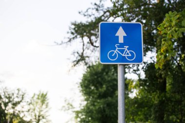 Mavi Kare Yol İşareti Gökyüzüne yakın bisikletçiler için Lane Bulutlar ve ağaçlarla bulanık arkaplan