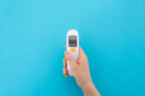 Infrared non-contact thermometer for temperature measurement. The concept of an electronic device to check Your health. Isolated on a blue background