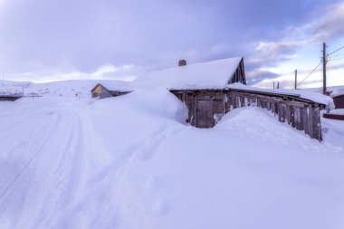 Barents Denizi kıyısındaki eski balıkçı köyünde karla kaplı bir kulübe, Kola Yarımadası, Teriberka, Rusya