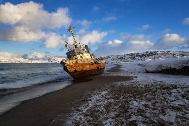 Yan yatmış bir balıkçı teknesi, Barents Denizi kıyısında bir fırtınayla karaya vurmuş, Kola Yarımadası, Teriberka, Rusya