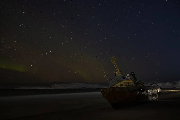 星空の中の極光 漁船が横になり バレンツ海の岸の嵐で流された ロシアのテリベルカ — ストック写真