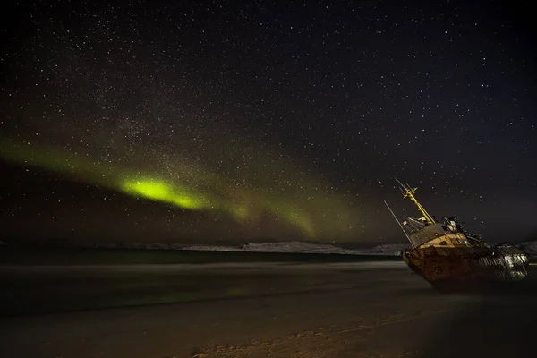 星空の中の極光 漁船が横になり バレンツ海の岸の嵐で流された ロシアのテリベルカ — ストック写真