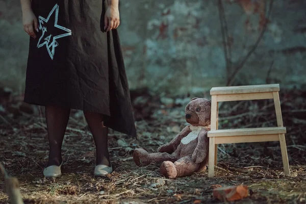 Meisje Staat Naast Een Teddybeer Zittend Grond Vlakbij Een Houten Stockfoto