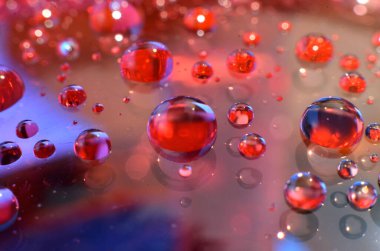 Bir bardağa iliştirilmiş parlak berrak su noktası, camdaki renkle aynı rengi yansıtır. Dekorasyondaki gibi güzel bir arka plana.