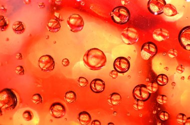 Bir bardağa iliştirilmiş parlak berrak su noktası, camdaki renkle aynı rengi yansıtır. Dekorasyondaki gibi güzel bir arka plana.