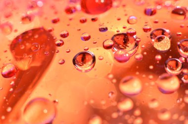 Bir bardağa iliştirilmiş parlak berrak su noktası, camdaki renkle aynı rengi yansıtır. Dekorasyondaki gibi güzel bir arka plana.