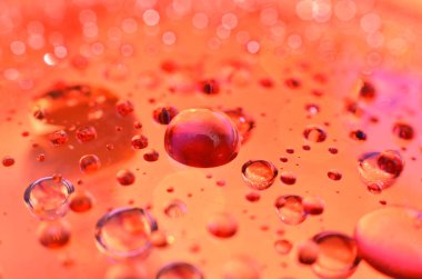 Bir bardağa iliştirilmiş parlak berrak su noktası, camdaki renkle aynı rengi yansıtır. Dekorasyondaki gibi güzel bir arka plana.