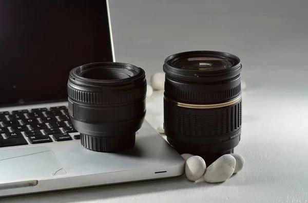 a pair of black colored camera lenses on a silver laptop with white bases of white round stone