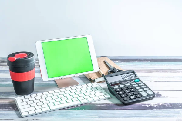 Stationery, reusable cup, keyboard and mobile tablet with green screen