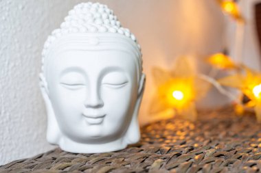 Minyatür beyaz Buddha kafa ve yüzü. Aydınlatılmış arka plan. Ev dekorasyonu süslemeleri.