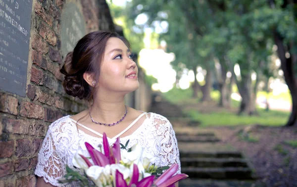 Asiatische Dame im Brautkleid mit Blumenstrauß. — Stockfoto