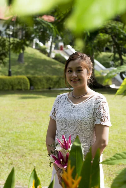 Gelinlikli Asyalı kadın elinde bir buket çiçek tutuyor. Açık hava bahçe park portresi. Doğal gerçek insanlar.. — Stok fotoğraf