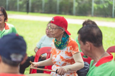 Yaşlılardan oluşan bir grup emekli Asyalı kadın müzik aleti çalıp hayattan zevk alıyor.