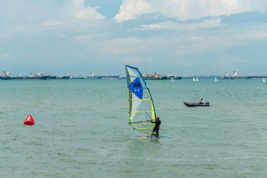 Spor adamı ve kadın rüzgar sörfçüsü gölde rüzgar sörfü yapıyor.