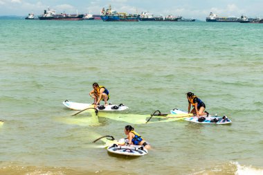 Erkek ve kadın rüzgar sörfçüsü lagün denizinde sörf yapıyor.