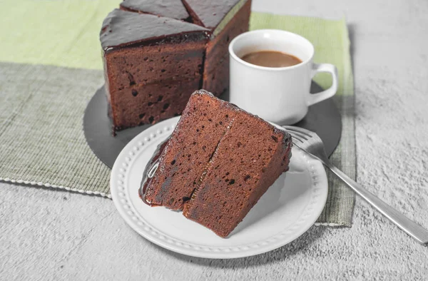 Австрийский шоколадный торт с тонким слоем абрикосового джема и чашкой кофе . — стоковое фото