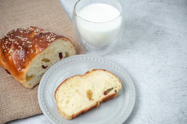 Kahvaltı sofrada hazır olsun. Somun, bir dilim kuru üzümlü ekmek ve bir fincan taze süt..