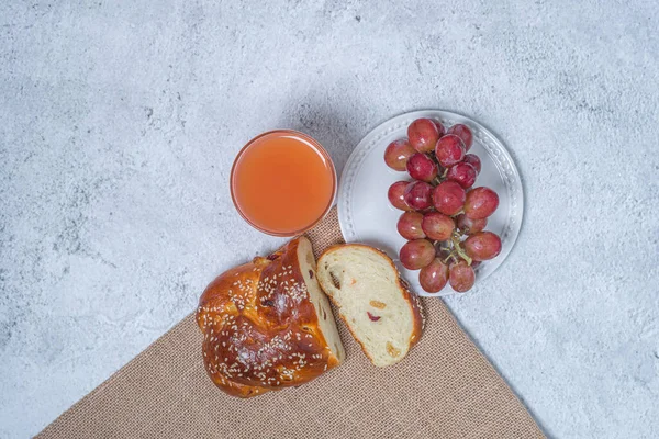 Pequeno-almoço na mesa. Conceito de leigos planos. Uvas no prato, pão de passas e um copo de suco de toranja . — Fotografia de Stock