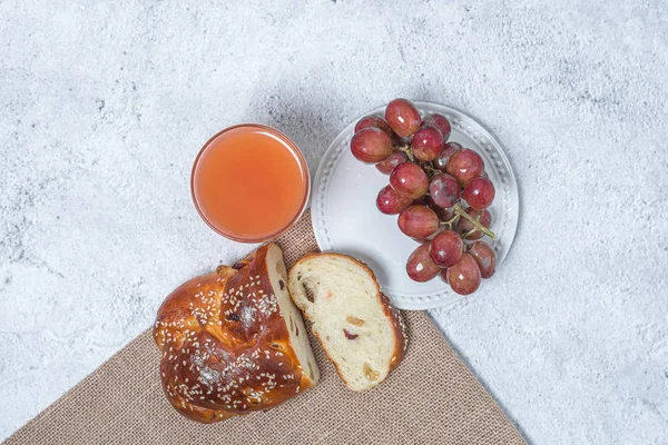 Pequeno-almoço na mesa. Conceito de leigos planos. Uvas no prato, pão de passas e um copo de suco de toranja . — Fotografia de Stock