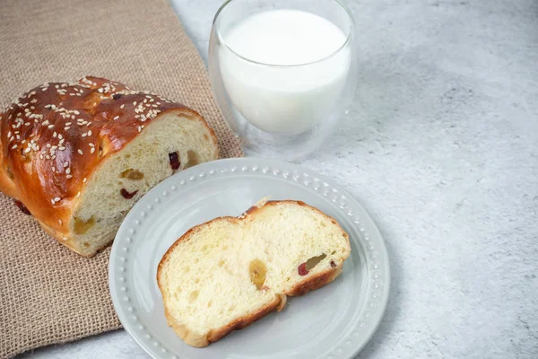 Reggeli villásreggeli az asztalon. Kenyér, egy szelet mazsolás kenyér tányéron és egy csésze friss tej.. — Stock Fotó