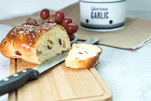 Home-baked raisins bread, knife and a bunch of grapes. Breakfast brunch on table. — Stock Photo, Image