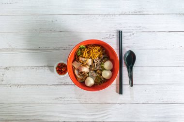 Asia Singapore dry noodle with fish ball minced pork with cut red chilli padi. Flat lay top view. clipart