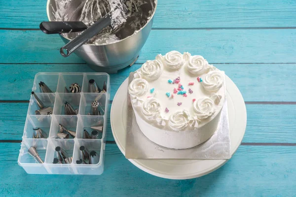 Cake frosting making baking mixer bowl, and box of piping nozzles on kitchen table — ストック写真