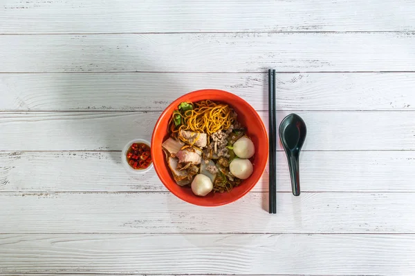 Asia Singapore dry noodle with fish ball minced pork with cut red chilli padi. Flat lay top view.