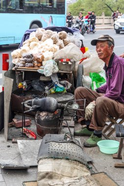 Asyalı yaşlı adam yerel sokak atıştırmalıkları yapıyor geleneksel yöntemlerle patlamış mısır yiyor.