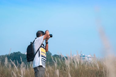 Asyalı olgun erkek, dijital DSR kamerasıyla doğa manzarası fotoğrafları çekiyor.