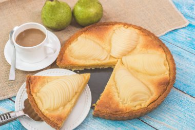Lezzetli ev yapımı haşlanmış armutlu turta, Tarte Bourdaloue olarak bilinir, bir fincan kahve latte. Fransız popüler tarifi Paris 'teki bir sokaktan geliyor. Yemek masa konsepti.