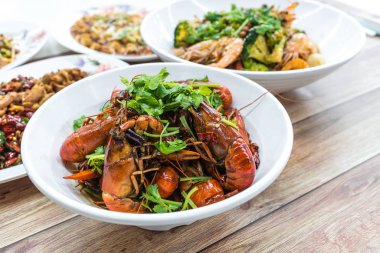 Chongqing Sichuan baharatlı kurutulmuş biberli küçük ıstakozlar ve arka plandaki diğer yemekler. Çin restoranında yemek fotoğrafçılığı..
