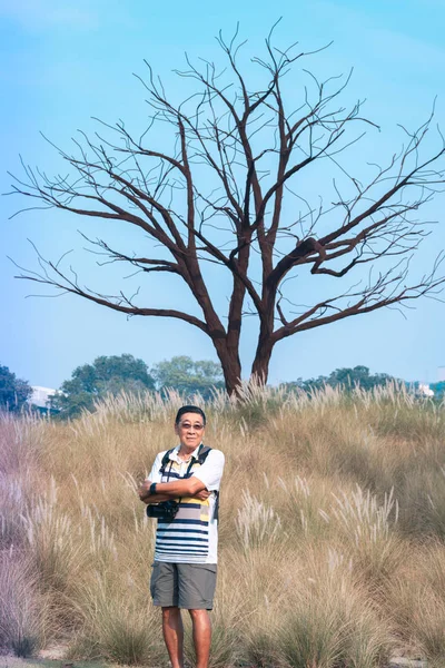 Ein gesunder asiatischer erwachsener Mann posiert in einem Park für die Kamera. Er liebt die Naturfotografie und genießt sein Rentnerleben. Kranken- & Versicherungskonzept. — Stockfoto
