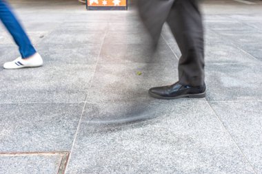 Kimliği belirsiz insanların alt bacaklarının hareket hareketi bulanıklaşır. Yoğun Asya şehrinde gündüz vakti aceleyle yürürler.