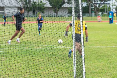 Seçici odaklanma. Bulanık arka plan. Futbol kalesinin arka planı ve Asyalı erkek kaleci ve diğer oyuncular.
