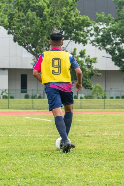 Stadyum sahasında top süren tanınmamış bir Asyalı futbolcu.