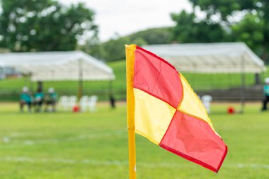 Ön planda futbol sahası bayrağı. Geçmişi tanınmayan futbolcularla bulanık. Spor ve insanlar teması.