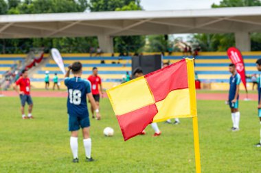 Ön planda futbol sahası bayrağı. Geçmişi tanınmayan futbolcularla bulanık. Spor ve insanlar teması.