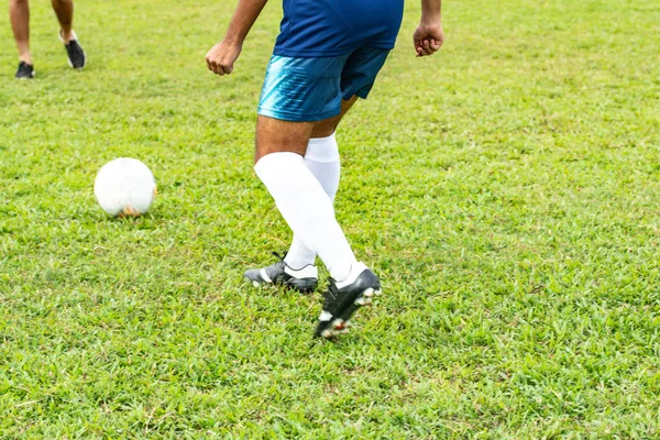 Motion blurred photo of lower back view of an unrecognisable soccer player in blue kicking football with his left leg — Stock Photo, Image