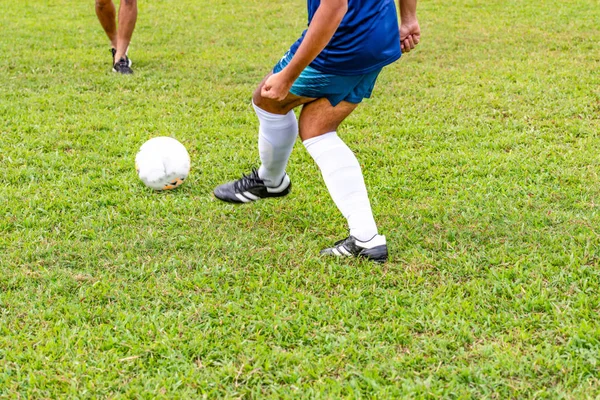 Motion blurred photo of lower back view of an unrecognisable soccer player in blue kicking football with his left leg — Stock Photo, Image