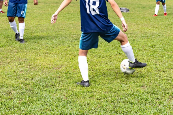 Visão traseira inferior de um jogador de futebol não identificado em azul no campo de futebol. Ele está a parar o futebol com a perna direita. . — Fotografia de Stock