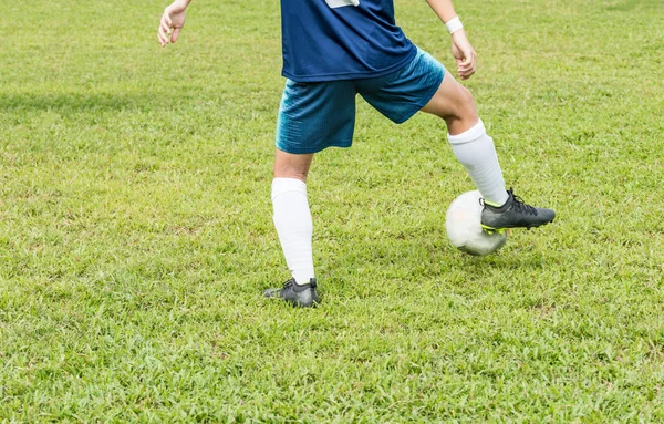 Futbol sahasında kimliği belirlenemeyen mavili bir futbolcunun arka görüntüsü. Sağ bacağıyla topu durduruyor..