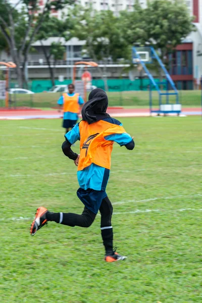Motion blur back view of one muslim female soccer player wearing hijab running across the field — Stock Photo, Image
