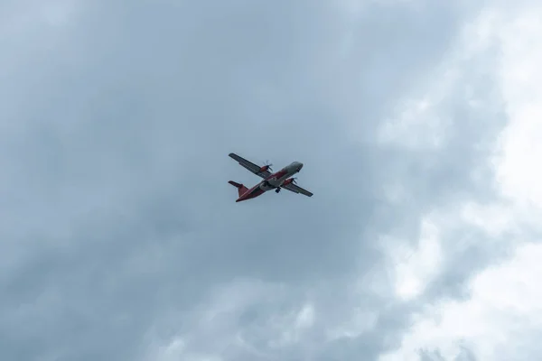 Bottom up view of aeroplane flying past in the blue sky on a cloudy day — Stock Photo, Image