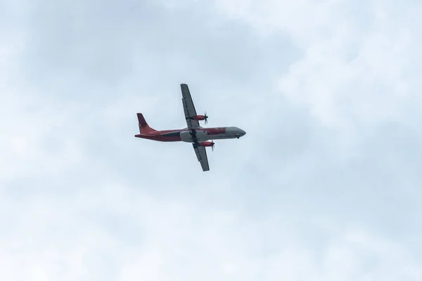 Bodem-up zicht op vliegtuig vliegen langs in de blauwe lucht op een bewolkte dag — Stockfoto