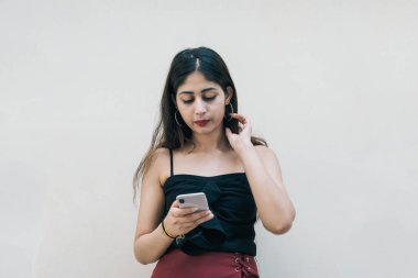 Asyalı bir kadın akıllı cep telefonunu kullanıyor, mesajlaşıyor, arka planda izole edilmiş. Uzaktan çalışan profesyonel teknoloji ve internet kullanımı.